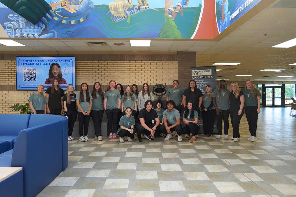 Large group of students posing  in front of the success bell.