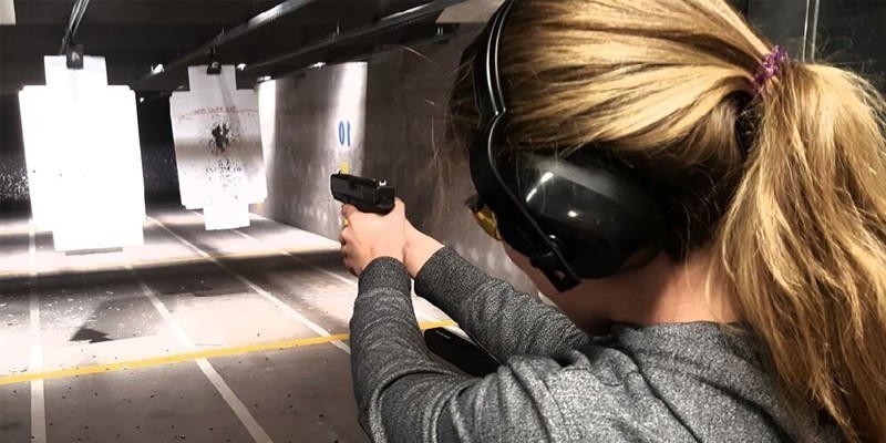 Woman shooting a handgun at a paper target in a firing range