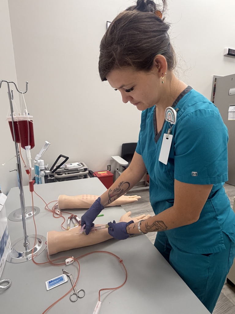 A student practicing phlebotomy skills on a mannequin