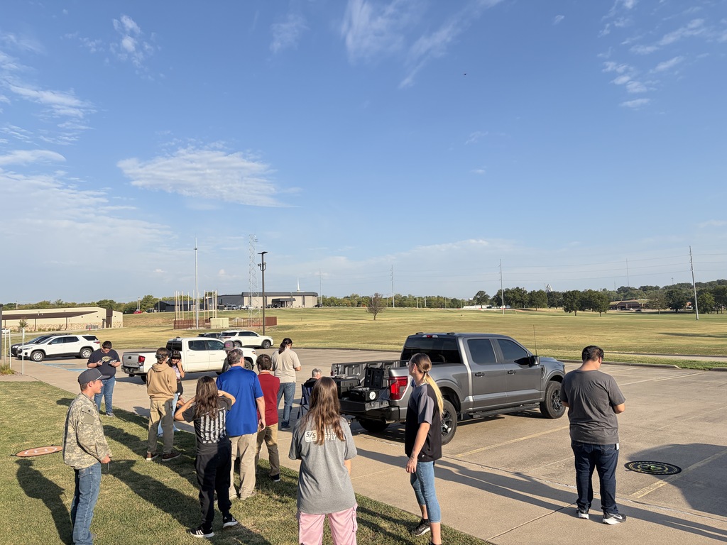 Students standing in a group watching drones fly.