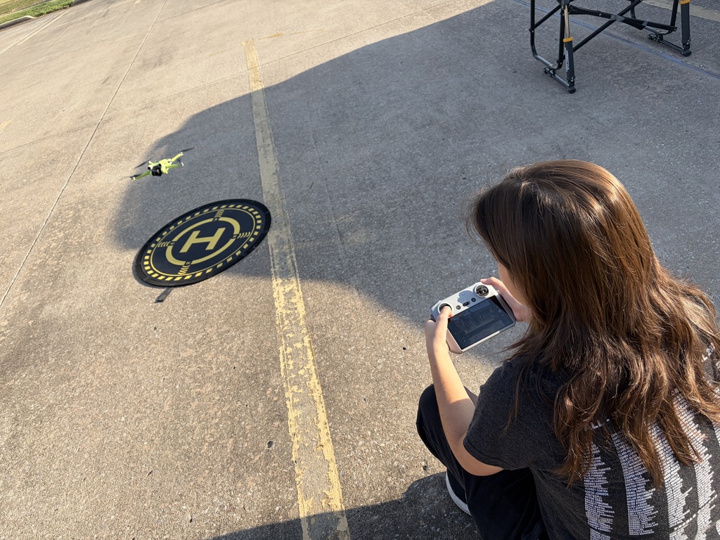 Student landing a drone on a pad in a parking lot