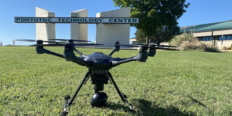 Picture of a drone on the ground in front of a sign that says Pontotoc Technology Center