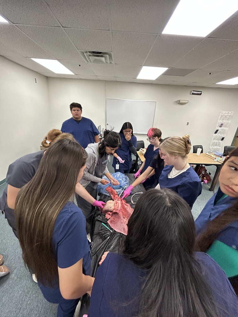 Students standing around a lab table with demonstration occuring
