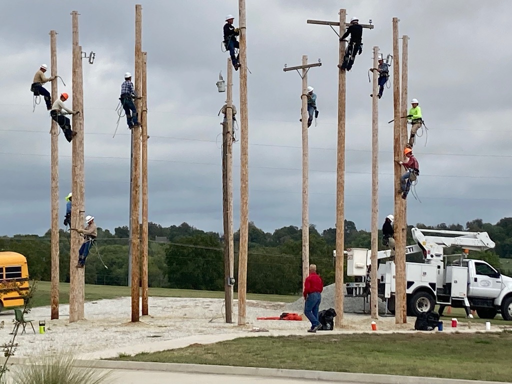 Several people climbing electrical poles in a practice yard