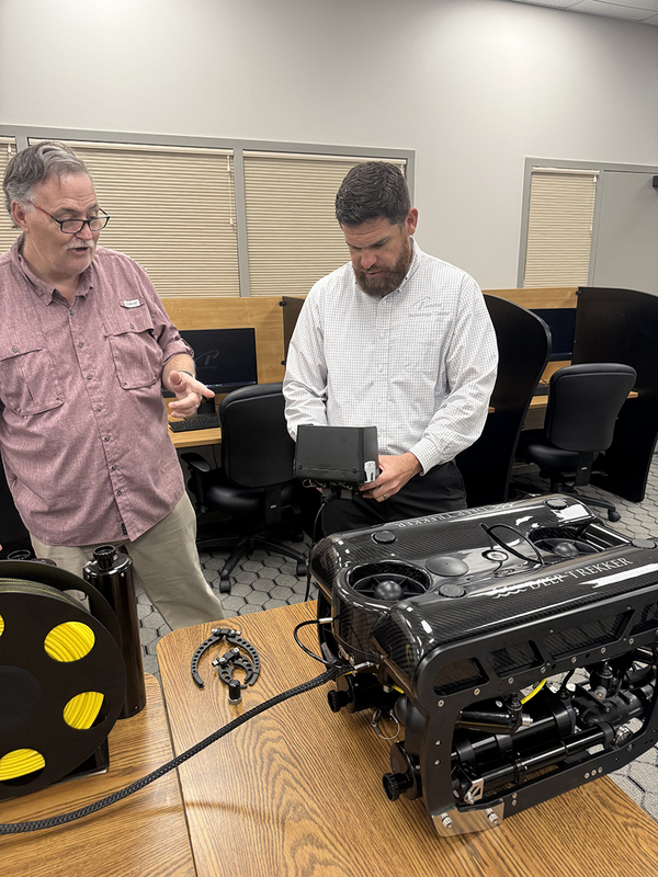 Two people looking at a submersible drone on a table top