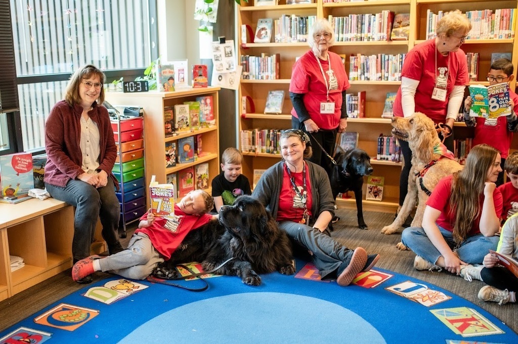 Students and paraeducators in the library with dogs for Read to Rover