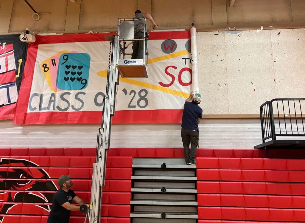 Members of the PT Schools all-star maintenance team hanging the colorful class banners in preparation for the afternoon Homecoming Assembly.