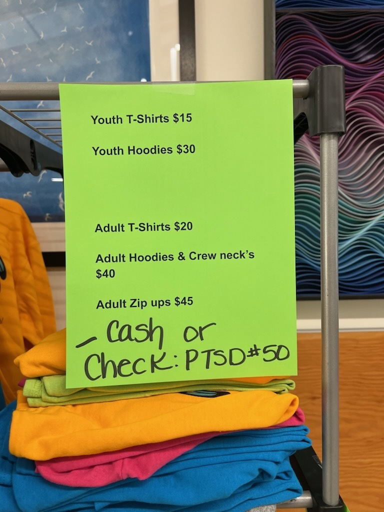 A photo of a lime green sign stating prices of the Eagle Wear at Salish Coast.