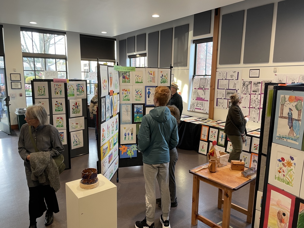 People walk thru the exhibit looking at the art