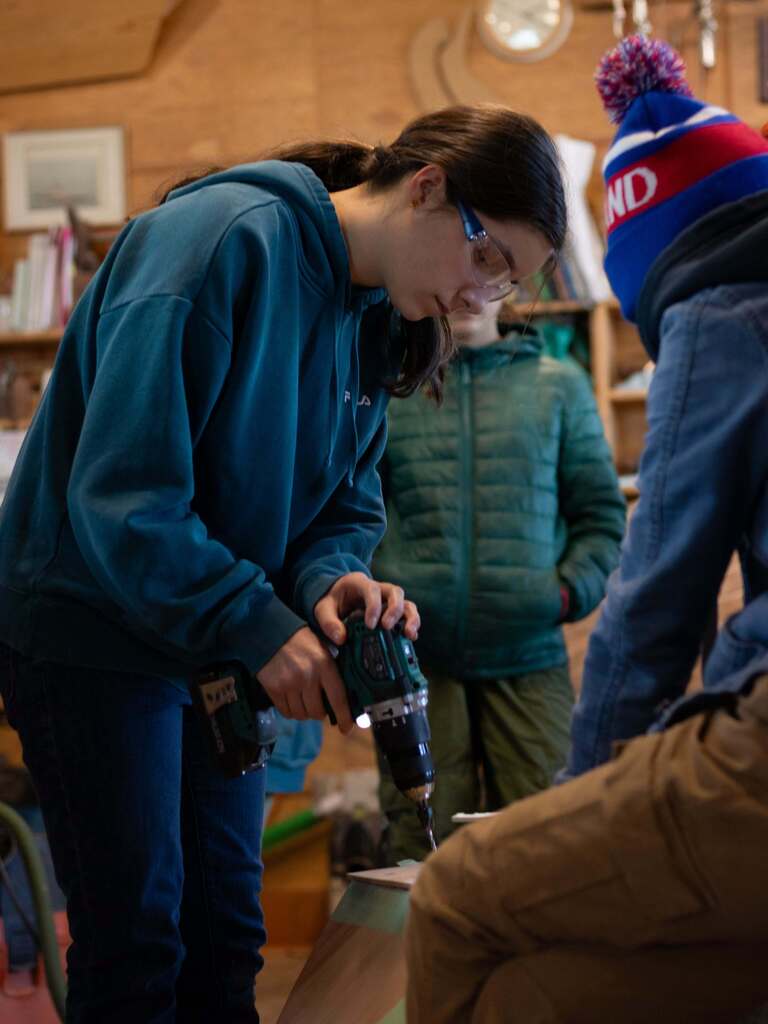 Student using a drill to create boat at NW Maritime Center