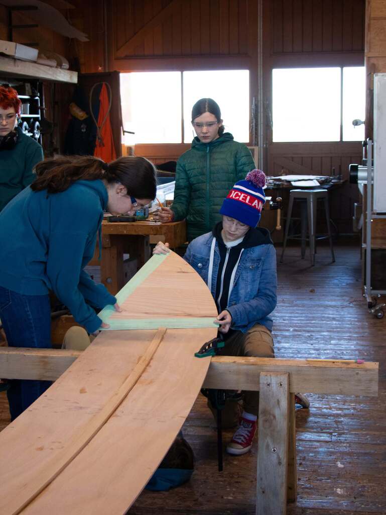 Three students working together to build a boat