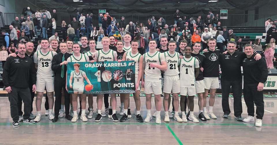 basketball team holding banner for student grady karrels who reached 1000 points