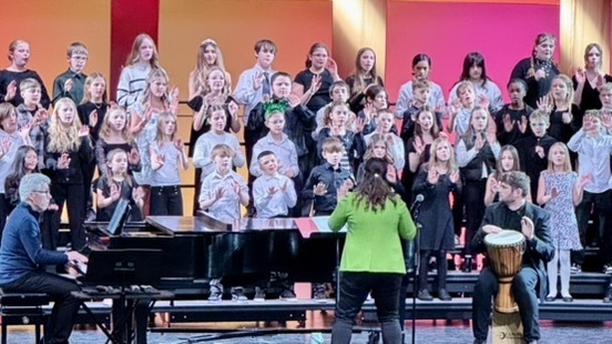 Choir director in front of fifth grade choir on risers