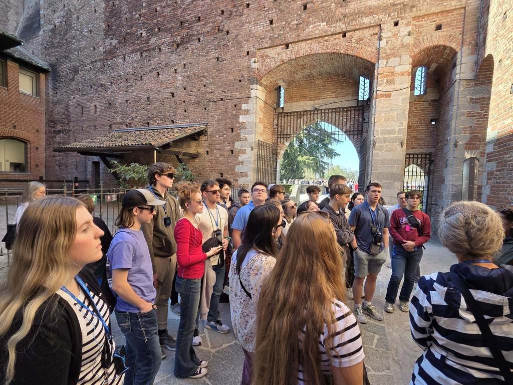 a group of students listening to a tour guide in italy