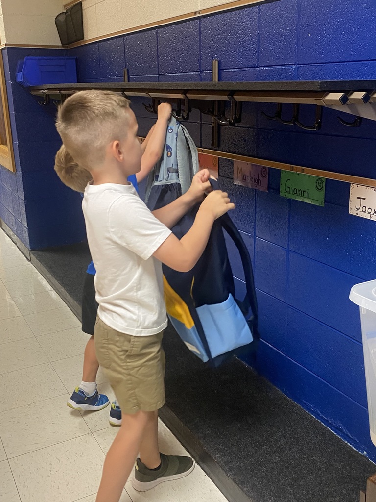 student hanging backpack