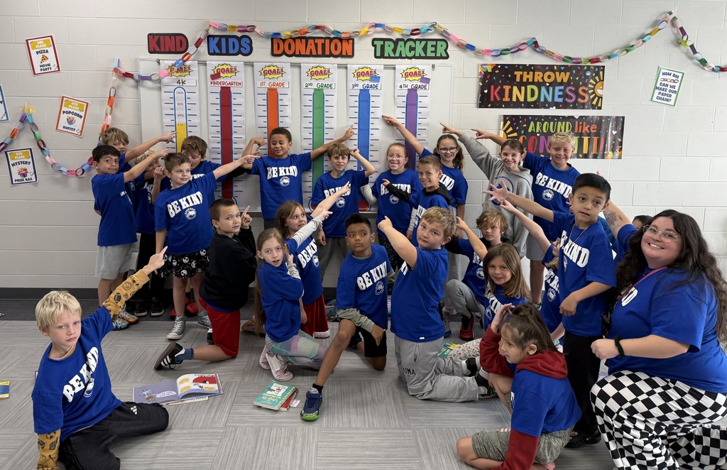 Students pointing to a Kind Kids Day Donation Tracker