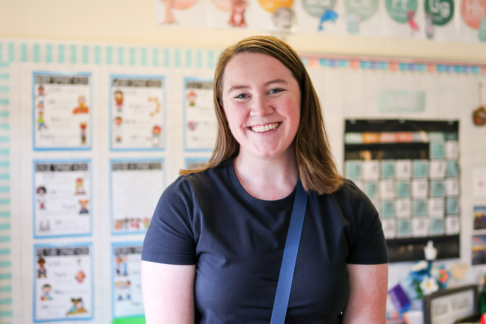 a woman poses for a photo inside a classroom
