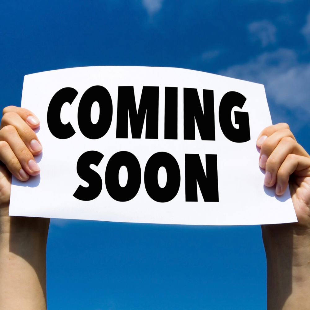 hands holding up a sign that says coming soon