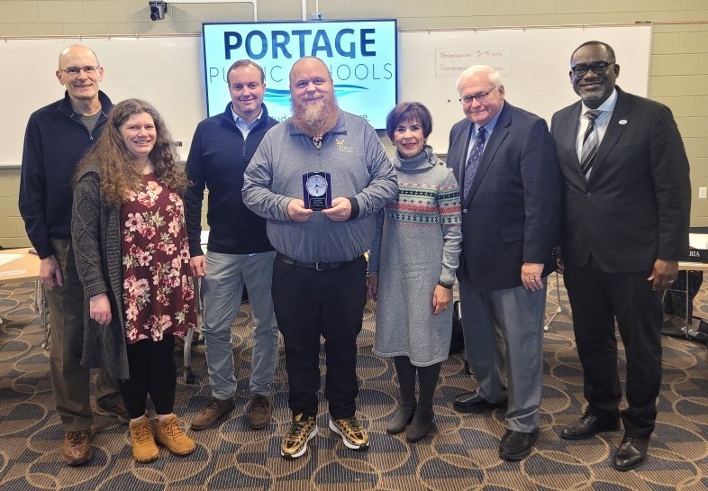 a man poses for a photo with board members