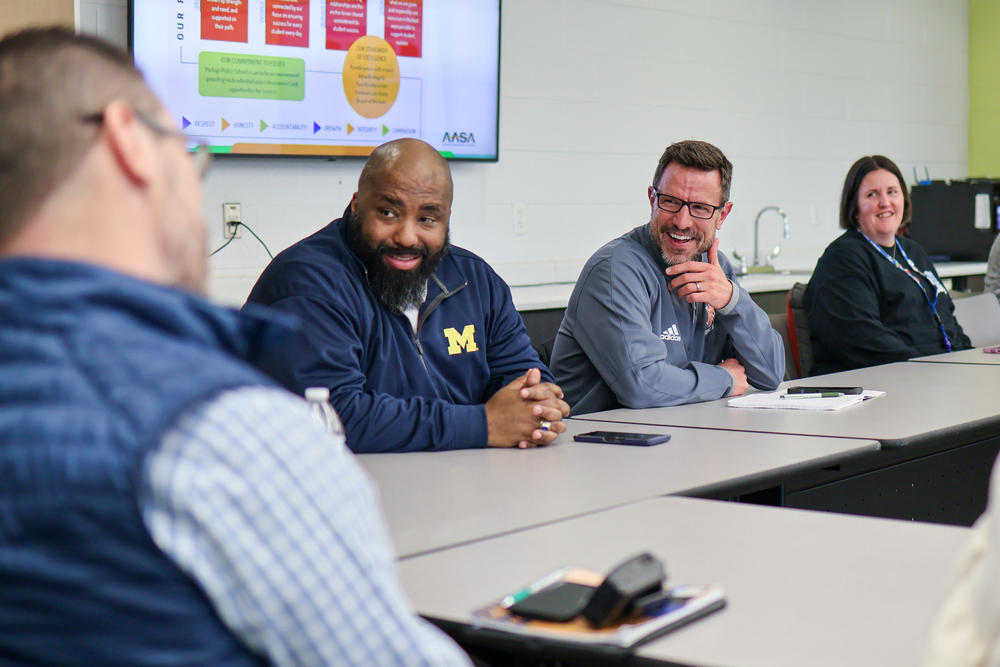multiple people laughing at a table in a school conference room