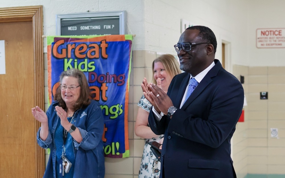 two men speak in a school hallway