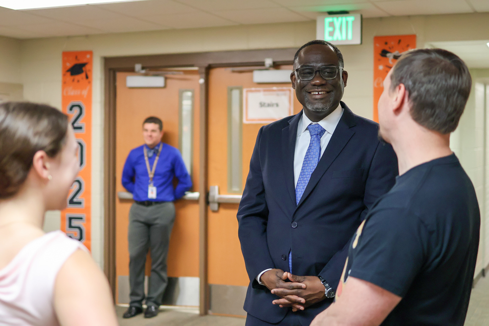 a man stands in a hallway talking to another man