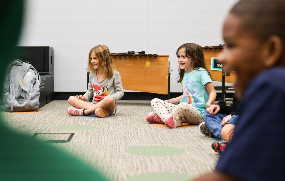 students sit on the floor of a music classroom