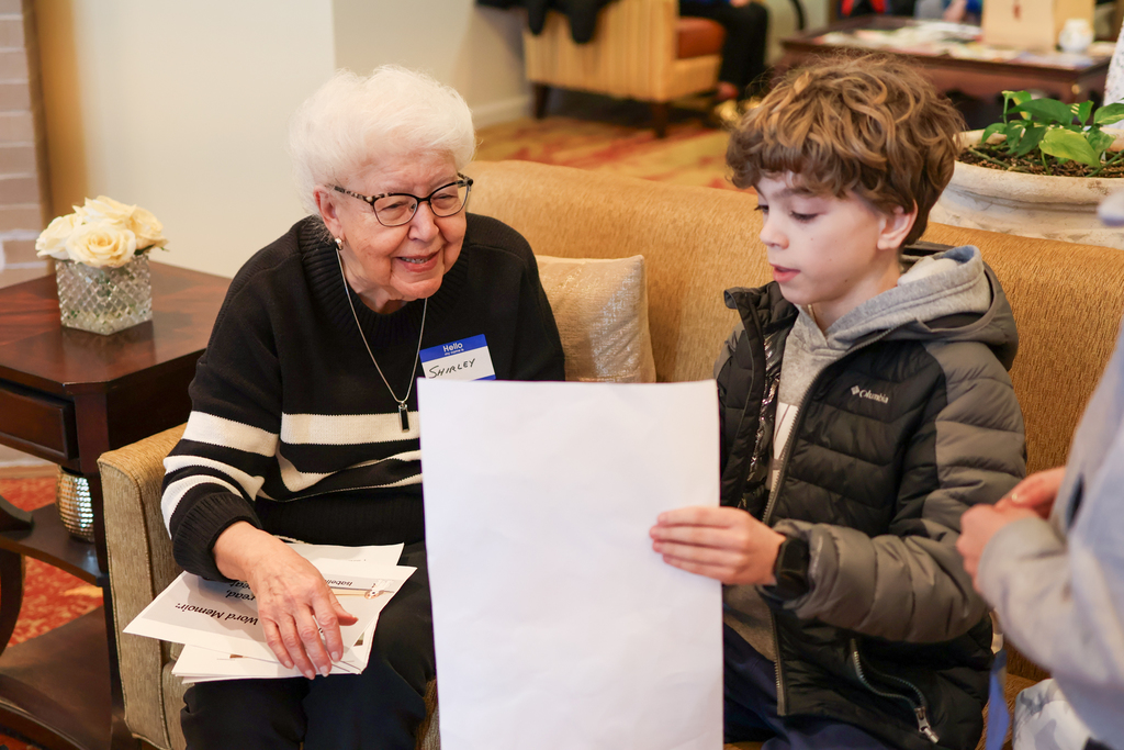 a young boy shows off a project to an elderly woman