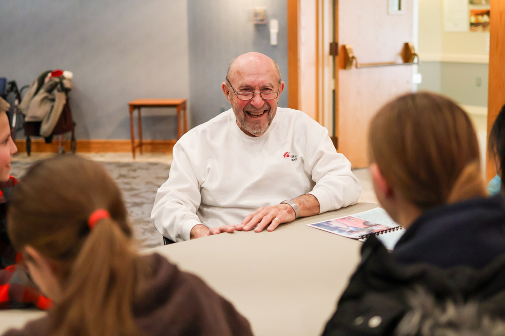an elderly man smiles at young students