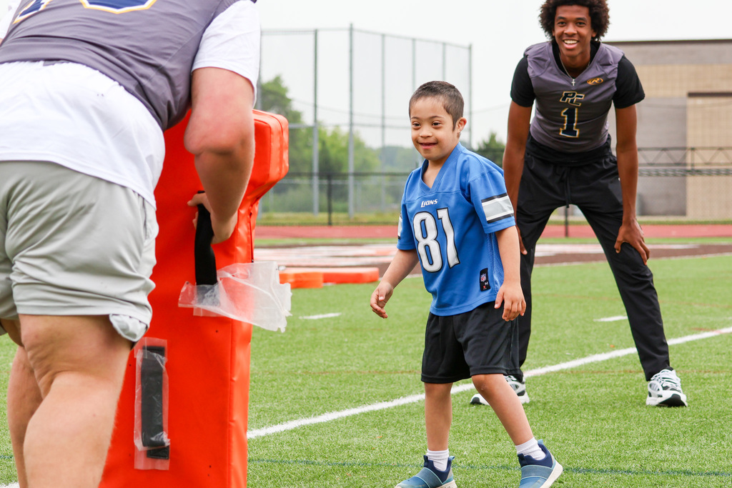 a boy prepares to run at a blocker in a football stadium