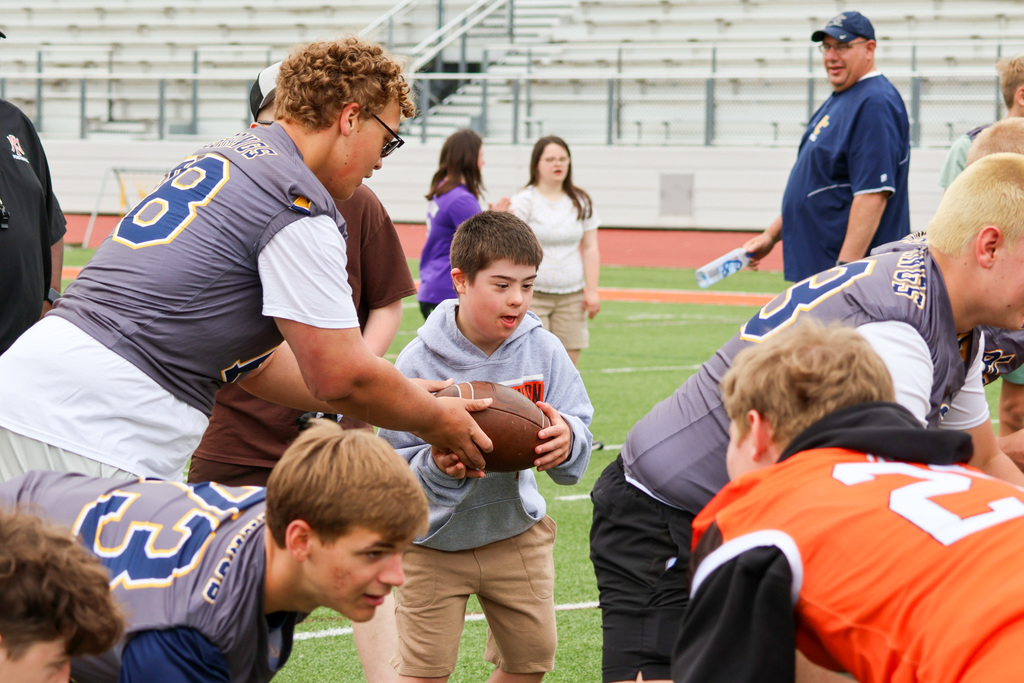 a boy catches a football surrounded by other football players