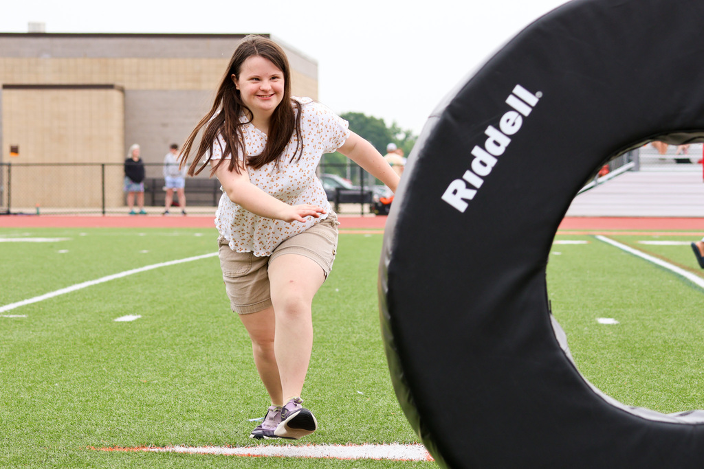 a girl runs toward a large mat on a football field