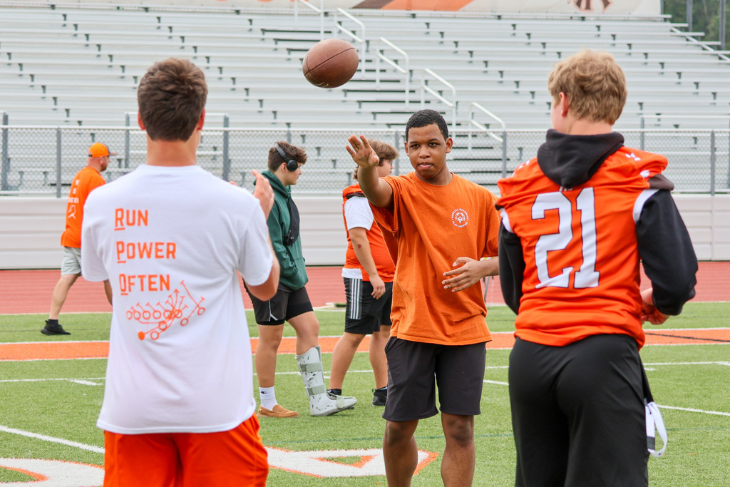 a boy throws a football to others in a football stadium