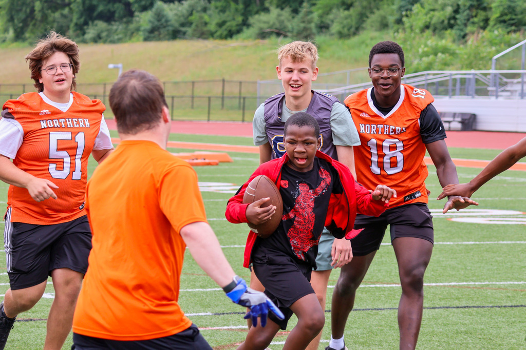 a boy runs through a group of other football players