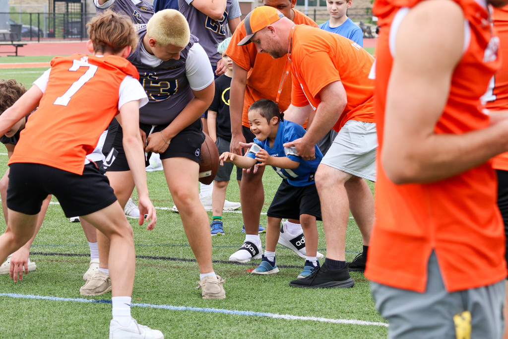 a boy catches a football surrounded by other football players