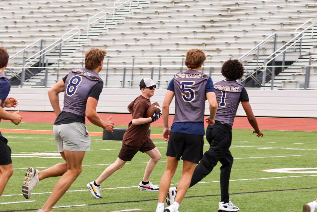 a boy runs with a football on a field