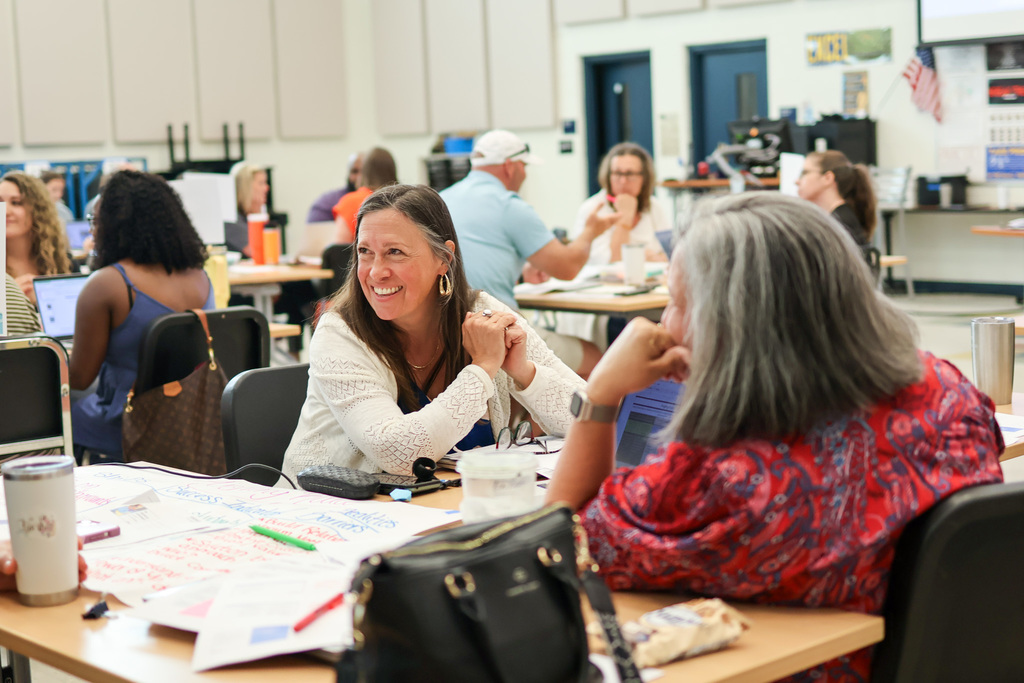 a woman smiles at someone sitting at a table