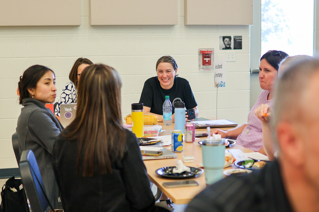 a woman smiles at others sitting around a table