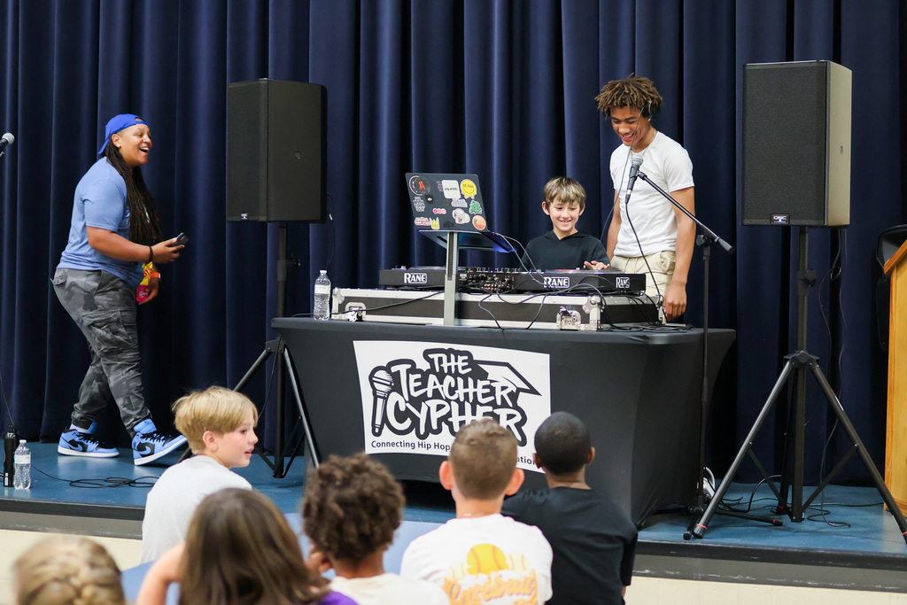 a boy helps a DJ make music on stage