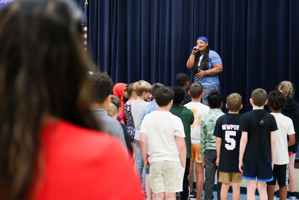 students listen to a rapper on stage
