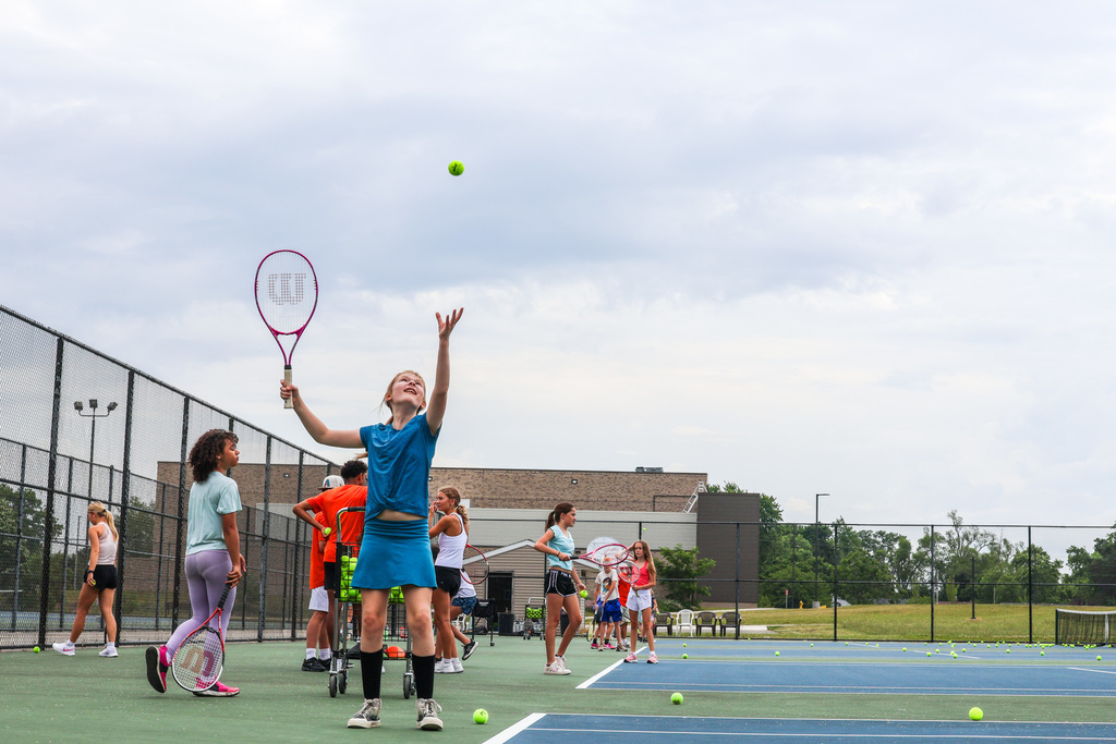 a girl serves a tennis ball