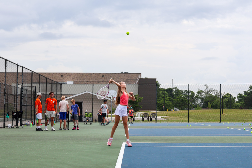 a girl serves a tennis ball