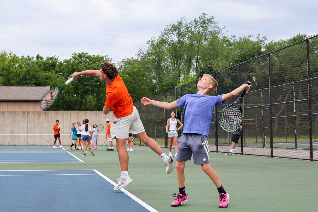 two boys serve tennis balls
