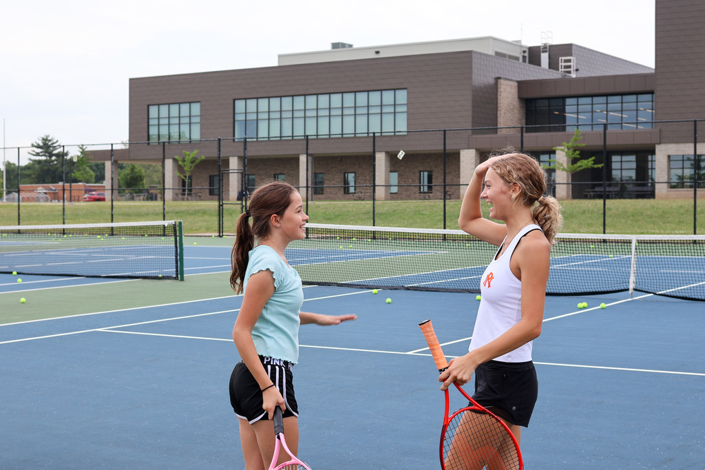 two girls high five on a tennis court