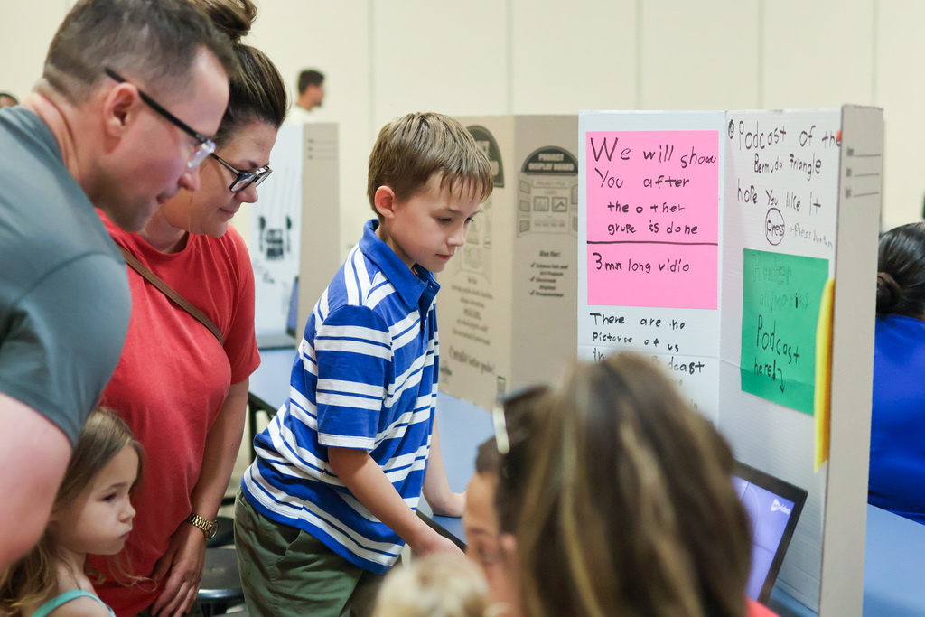 a boy shows off his presentation to his family