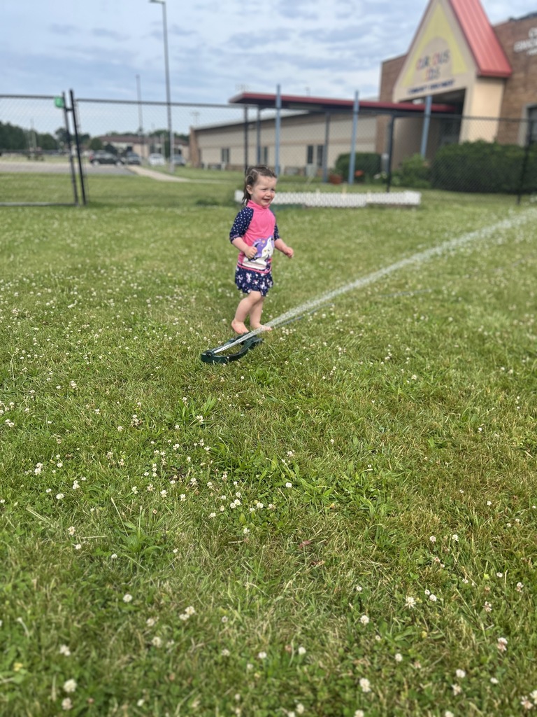 One toddler girl playing in the sprinkler.