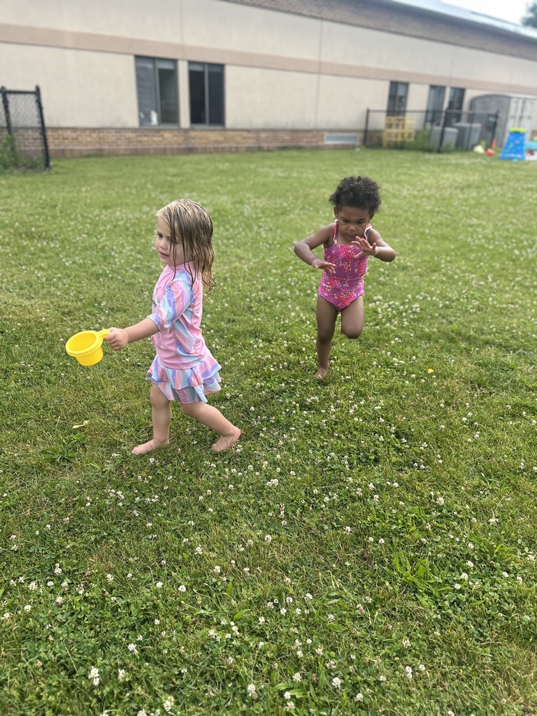 Two girls running in the sprinklers.