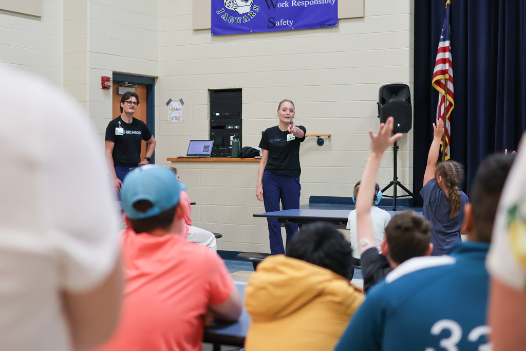 a woman points at students inside a school cafeteria