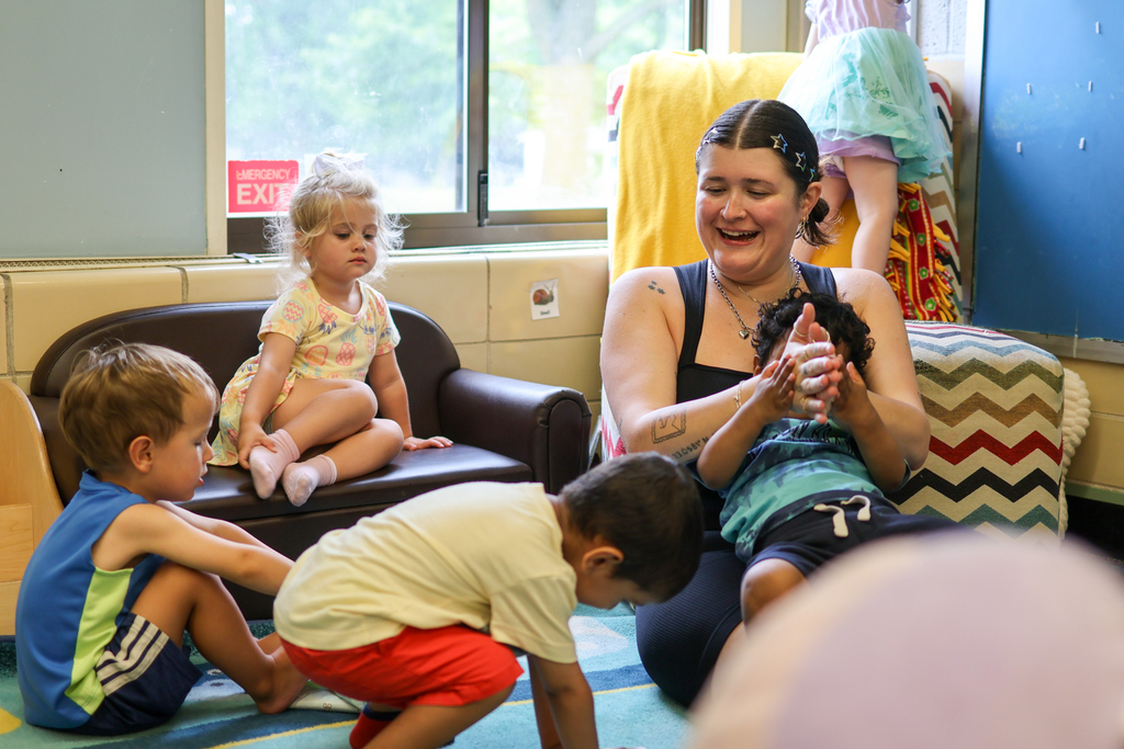 a teacher claps surrounded by little kids in a classroom