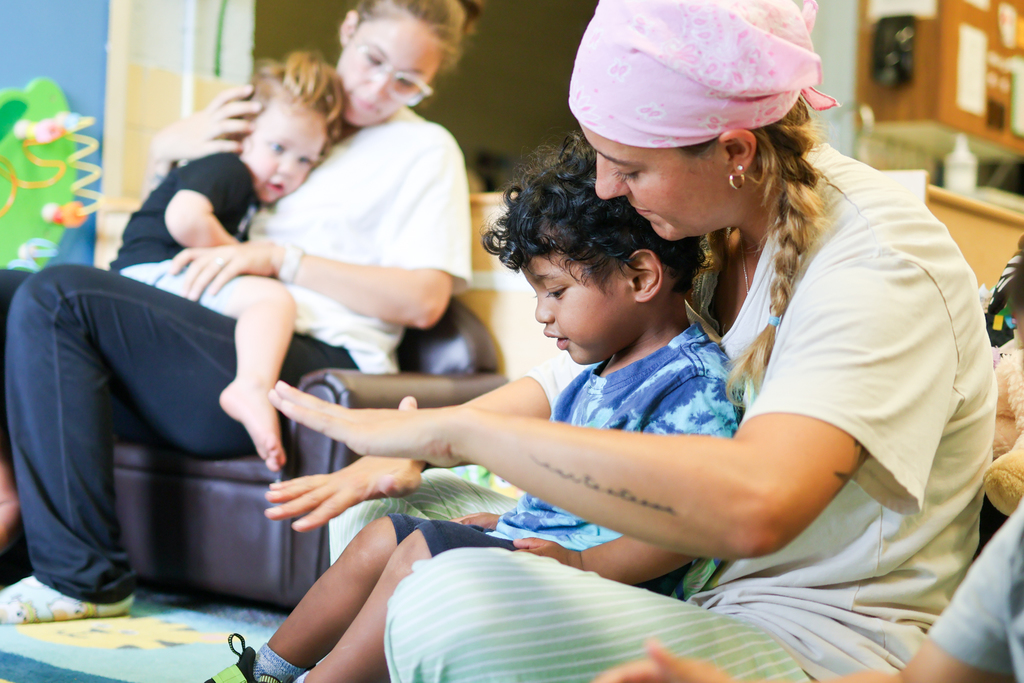 teachers hold toddlers inside a classroom